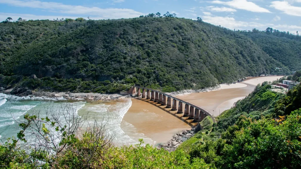 Knysna'da kıyı, demiryolu köprüsü ve yeşil yamaçlar