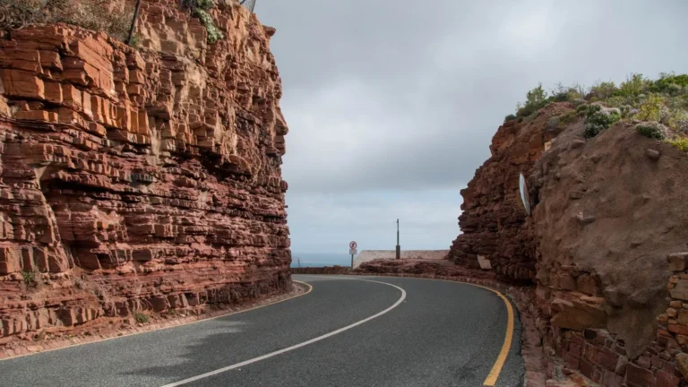 Cape Town'da Chapman’s Peak yakınında kırmızı kayalıklar arasından kıvrılan yol